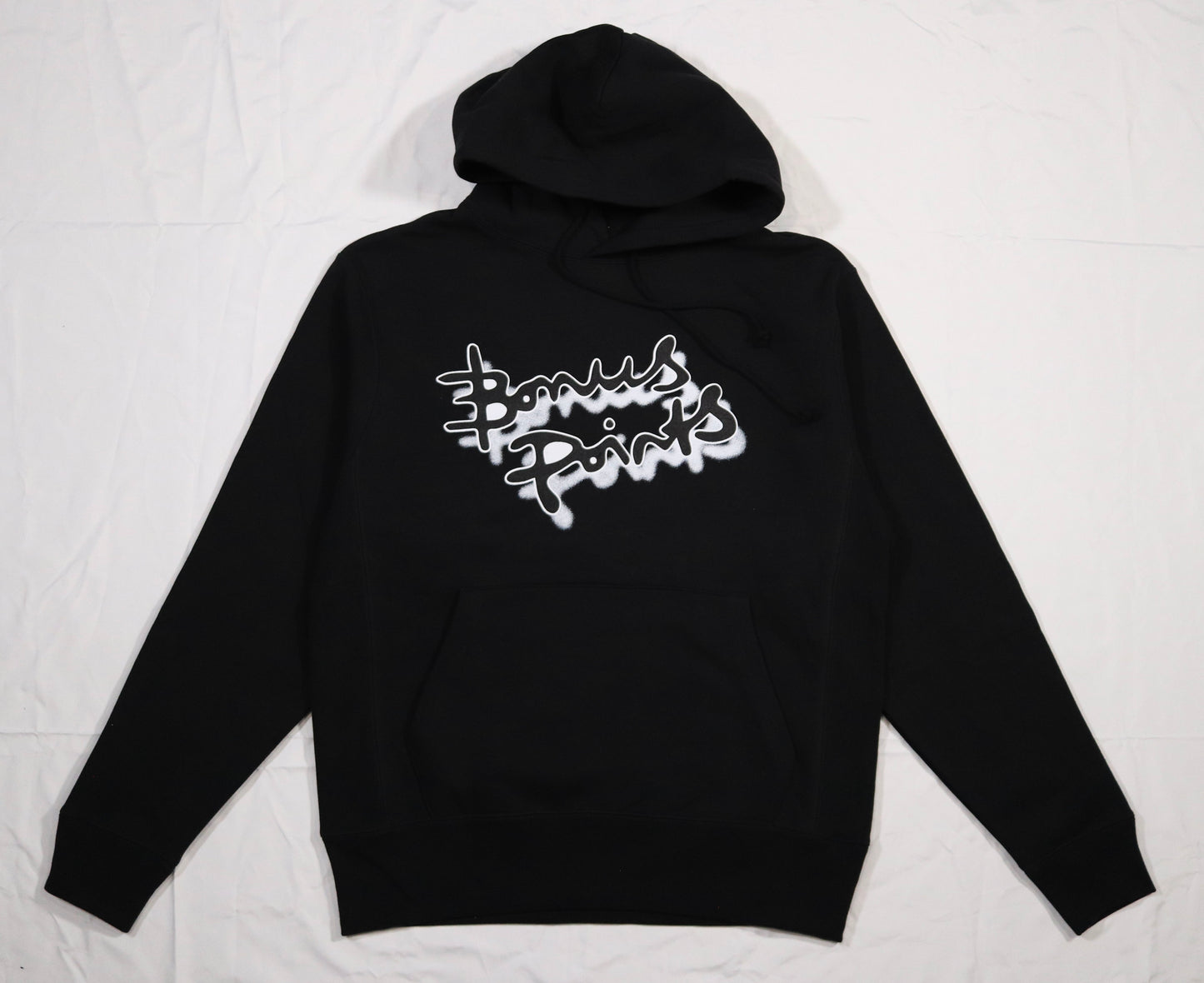 Flat lay of a cozy black pullover hoodie in a soft fabric, displayed on a clean white background. The hoodie features the Bonus Points Logo across the chest in black ink, with a white stroke outline, and a white drop shadow. Hoodie has a front pocket and adjustable drawstrings, showcasing its casual style.