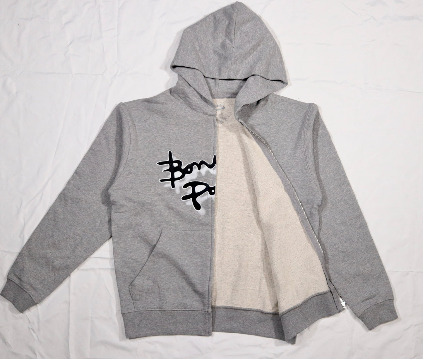 Flat lay of a open Gray Zip-up hoodie in a soft fabric, displayed on a clean white background. The hoodie features the Bonus Points Logo across the chest in black ink, with a white stroke outline, and a white drop shadow. Hoodie has two front pockets and chrome zipper.